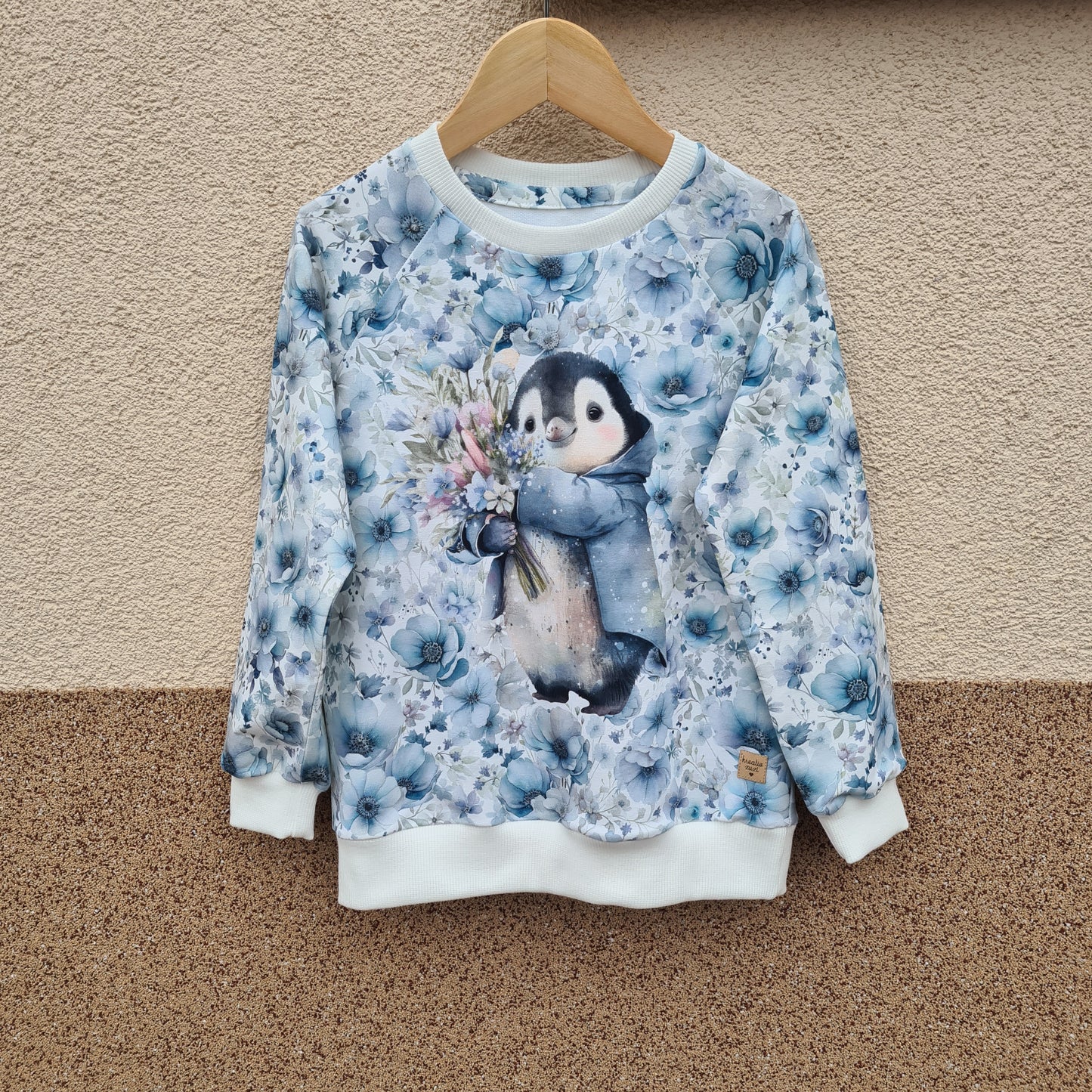 dievčenská detská handmade mikina s tučniakom vpredu so zimným vzorom na bielom podklade s modrými kvetmi, ideálna na zimné a vianočné obdobie